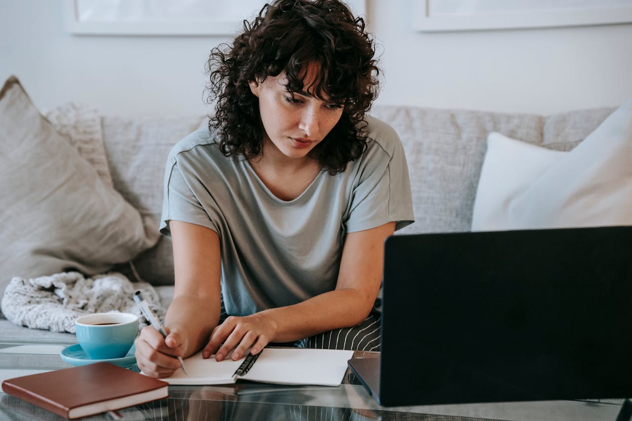 woman using laptop and writing on paper